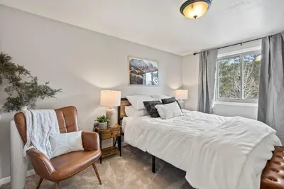 a bedroom with a bed and a chair and a window at Whispering Pines-Hot tub Getaway in Bailey