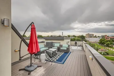 a patio with an umbrella and chairs on a balcony at Upscale Townhome w/ Stunning Rooftop Views in Denver