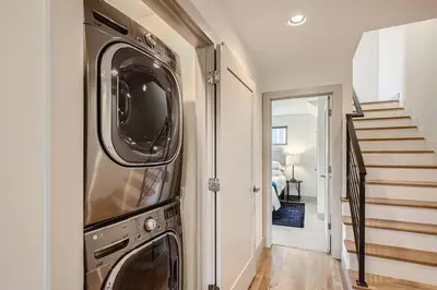a washer and dryer in a hallway with a staircase at Upscale Townhome w/ Stunning Rooftop Views in Denver