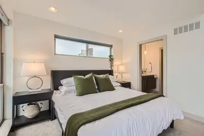 a bedroom with a large white bed with green pillows at Upscale Townhome w/ Stunning Rooftop Views in Denver