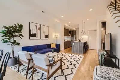 a living room with a blue couch and a kitchen at Upscale Townhome w/ Stunning Rooftop Views in Denver