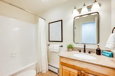 a bathroom with a sink and a mirror and a tub at Fraser Condo with Ski Shuttle and Resort Amenities! in Fraser