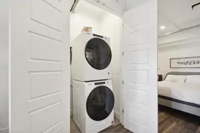 a washer and dryer in a white room with a bed at Brushed & Bold | RiNo Art Lofts in Denver