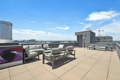 a rooftop deck with benches and a view of a city at Cowboy Muse | RiNo Art Lofts in Denver