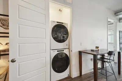 a laundry room with a washer and dryer next to a table at Cowboy Muse | RiNo Art Lofts in Denver