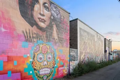 a mural of a woman with a skull on a wall at Cowboy Muse | RiNo Art Lofts in Denver