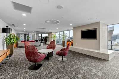 a lobby with red chairs and a tv on a wall at Spire - Unit 1810 in Denver