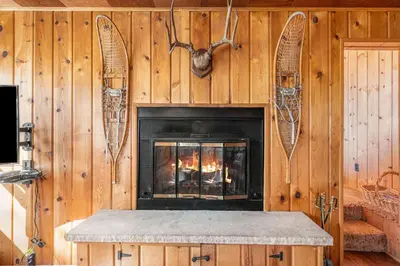 a living room with a fireplace in a wooden wall at Chasm Cabin -- 20-NCD0048 cabin in Estes Park