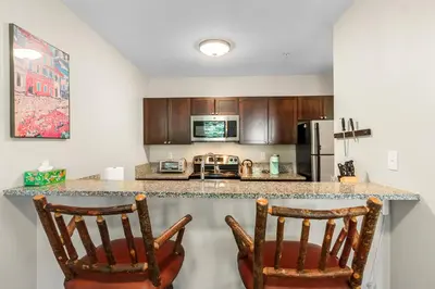 a kitchen with two chairs at a counter with a refrigerator at Alpine Ridge A25 by Great Western Lodging in Dillon