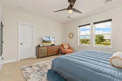 a bedroom with a blue bed and a chair and windows at Contemporary Gem - Rooftop Deck & Private Hot Tub! in Fort Collins