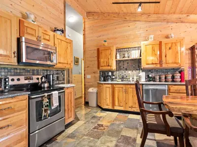 a kitchen with wooden cabinets and a table and a stove at Pine Haven Resort in Estes Park