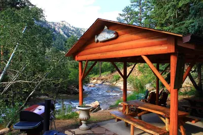 a wooden gazebo with a table and a river at Pine Haven Resort in Estes Park