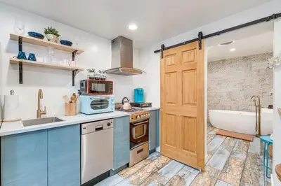 a kitchen with blue cabinets and a bath tub at Denver Tiny House Walk to Cafes, Bars, Eateries! in Denver