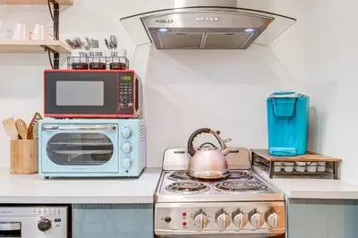 a kitchen with a microwave and a stove with a tea kettle at Denver Tiny House Walk to Cafes, Bars, Eateries! in Denver