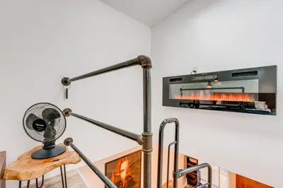 a fireplace in a living room with a fan at Denver Tiny House Walk to Cafes, Bars, Eateries! in Denver