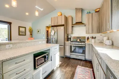 a large kitchen with white cabinets and wooden floors at Walk to Slopes Home with Hot Tub in Keystone in Keystone