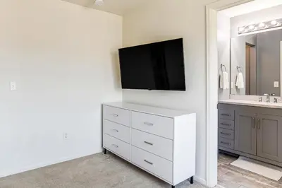 a bathroom with a white dresser with a tv on the wall at 6 Mi to DIA Denver Home with Fenced Yard and Fire Pit in Aurora