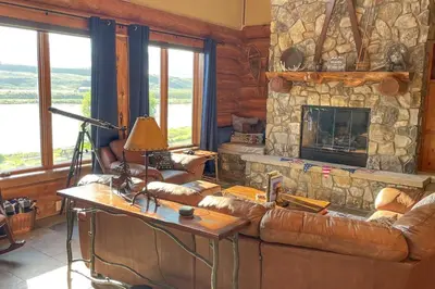 a living room with a couch and a stone fireplace at Bergamont Bliss in Tabernash