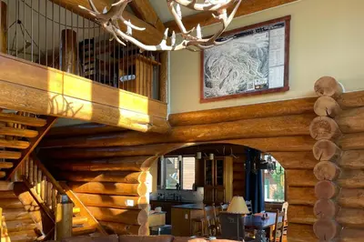 a dining room with a wooden staircase in a log house at Bergamont Bliss in Tabernash