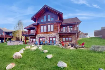 a log house on a hill with rocks in the yard at Bergamont Bliss in Tabernash