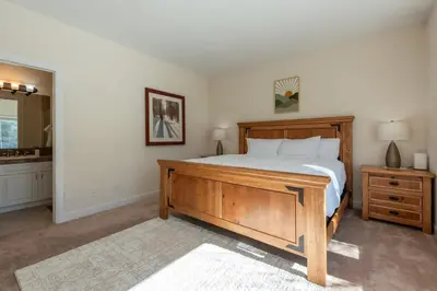 a bedroom with a large wooden bed and a bathroom at Luxurious 4BR Retreat - Pool Table & Chic Amenities in Boulder