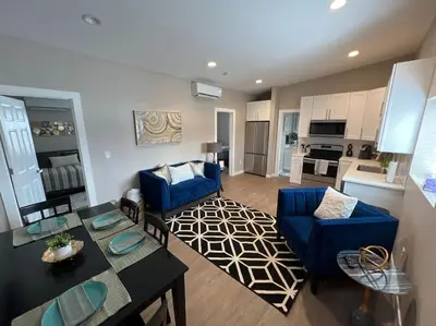 a living room with a blue couch and a dining room at Elegant & cozy 2 bed in Brighton