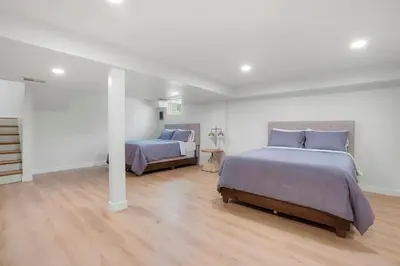 two beds in a white room with wood floors at Large Home, 2 Living Rooms, Great for Family/Pets! in Arvada