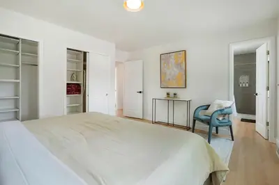 a white bedroom with a large bed and a blue chair at Large Home, 2 Living Rooms, Great for Family/Pets! in Arvada