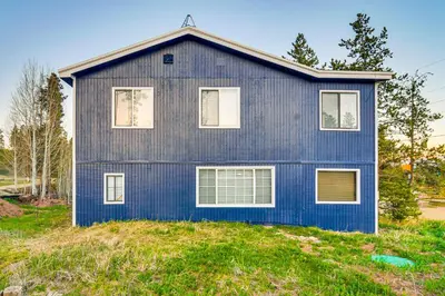 a blue house on top of a grass field at Tabernash Home about 13 Miles to Winter Park! in Tabernash