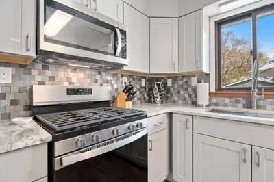a kitchen with white cabinets and a stove top oven at Spirit of the Rockies - Private Backyard & Hot Tub in Fort Collins