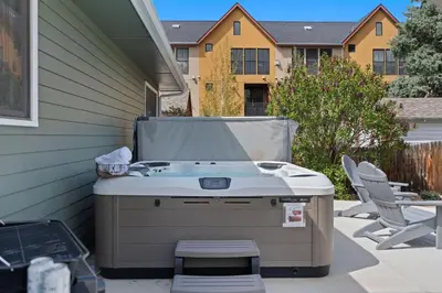 a barbecue on a patio with two chairs and a house at Spirit of the Rockies - Private Backyard & Hot Tub in Fort Collins