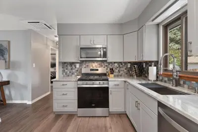 a kitchen with white cabinets and a stove top oven at Spirit of the Rockies - Private Backyard & Hot Tub in Fort Collins