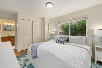 a white bedroom with a large bed and a window at Sherwood Cottage - Steps from Old Town & Poudre River in Fort Collins