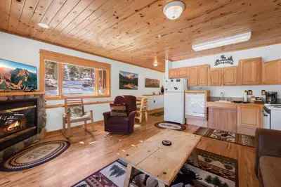 a kitchen and living room with a table and a refrigerator at Bugle Pointe B06 by Estes Park Condos in Estes Park