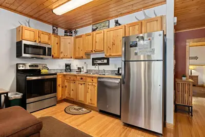 a kitchen with a stainless steel refrigerator and wooden cabinets at Bugle Pointe B16 by Estes Park Condos in Estes Park