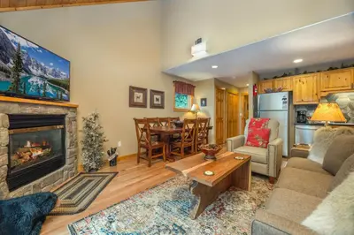 a living room with a fireplace and a dining room at Creekside Condos C by Estes Park Condos in Estes Park