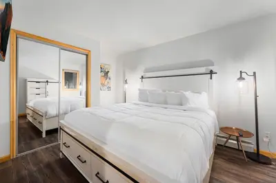 a white bedroom with a large bed and a mirror at Creekside Suites 16 by Estes Park Condos in Estes Park