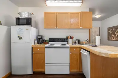 a kitchen with white appliances and wooden cabinets at Creekside Suites 16 by Estes Park Condos in Estes Park