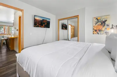 a white bedroom with a large white bed and a table at Creekside Suites 16 by Estes Park Condos in Estes Park