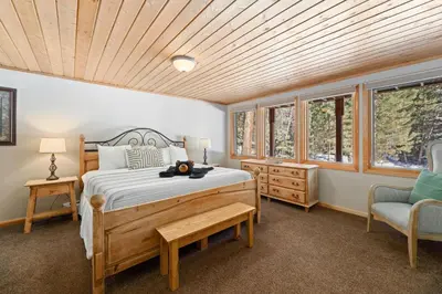 a bedroom with a bed and a chair and windows at Creekside Suites 01 by Estes Park Condos in Estes Park