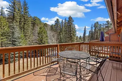 a patio with a table and chairs on a deck at Creekside Suites 03 by Estes Park Condos in Estes Park