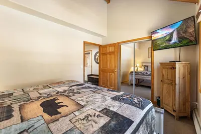 a bedroom with a large bed with a painting on the wall at Creekside Suites 03 by Estes Park Condos in Estes Park