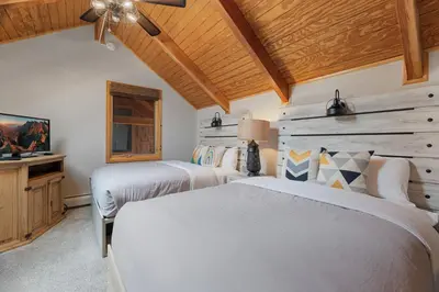 two beds in a bedroom with wooden ceilings at Creekside Suites 09 by Estes Park Condos in Estes Park