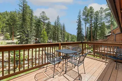 a patio with a table and chairs on a deck at Creekside Suites 09 by Estes Park Condos in Estes Park