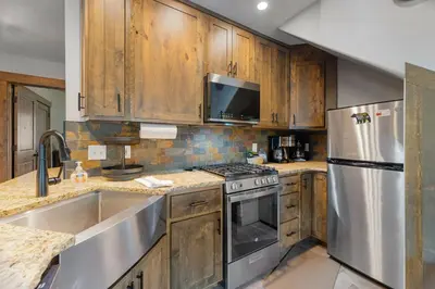 a kitchen with wooden cabinets and stainless steel appliances at Creekside Suites 09 by Estes Park Condos in Estes Park