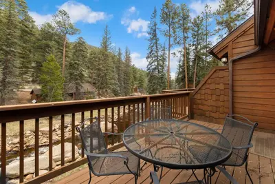 a patio with a table and chairs on a deck at Creekside Suites 10 by Estes Park Condos in Estes Park