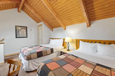 two beds in a room with wooden ceilings at Creekside Suites 10 by Estes Park Condos in Estes Park