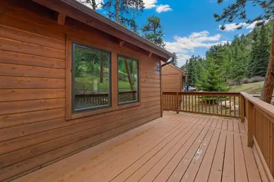 a cabin with a deck next to a building at Creekside Suites 11 by Estes Park Condos in Estes Park