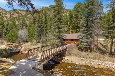 a bridge over a river in front of a house at Creekside Suites 18 by Estes Park Condos in Estes Park
