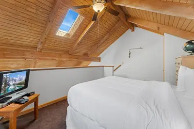 a bedroom with a white bed and a flat screen tv at Creekside Suites 18 by Estes Park Condos in Estes Park